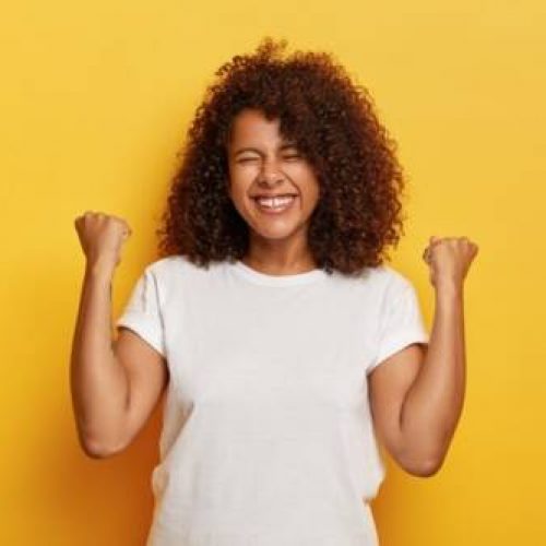 foto-isolada-de-linda-mulher-de-sucesso-com-cabelos-cacheados-levanta-os-punhos-cerrados-comemora-o-triunfo-ficando-muito-satisfeita-e-fe